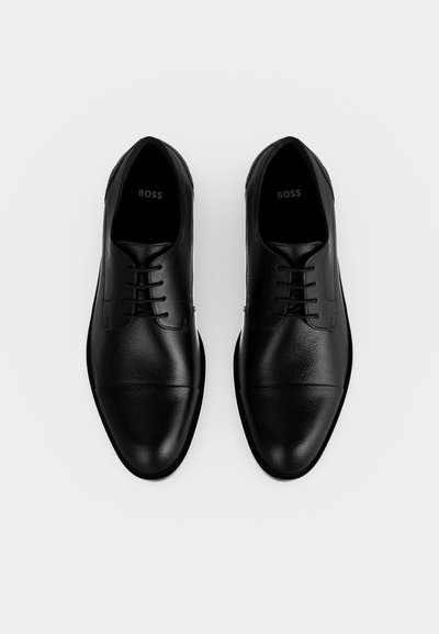Paire de chaussures habillées noires en cuir à lacets avec un bout lisse, vues de dessus sur fond blanc.