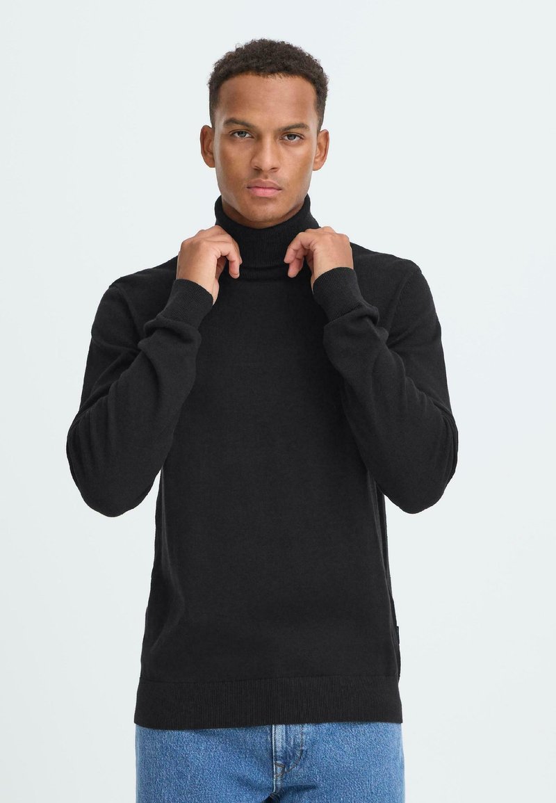 Schwarzer Rollkragenpullover aus weichem Strickstoff, mit langen Ärmeln, tailliertem Schnitt und gerippten Akzenten am Kragen und Saum.