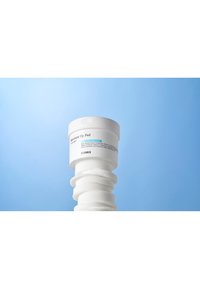 COSRX Moisture Up Pad, witte ronde container, textuurpads, minimalistisch ontwerp met turquoise accent, op een lichtblauwe achtergrond.