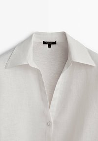 Witte linnen shirt met een klassieke kraag, knopen aan de voorkant en een gladde textuur. Heeft een schoon, minimalistisch ontwerp zonder patronen.