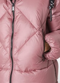 Rosa puffjacka med diamantquiltmönster, främre dragkedja och svarta detaljer. Har elastiska muddar och en ficka med dragkedja.