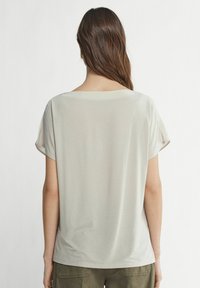 Jasnoszara koszulka z luźnym krojem, okrągłym dekoltem i krótkimi rękawami. Wykonana z miękkiej tkaniny o gładkiej fakturze. Prosty i minimalistyczny design.
