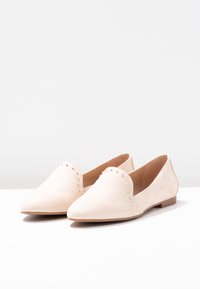 Ballerines en cuir suédé rose clair avec un bout pointu et un découpage en forme de cœur, rehaussées de petits clous dorés le long du bord. Semelle plate.