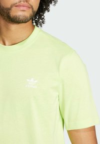 Light green cotton t-shirt with short sleeves and a crew neckline. Features small white adidas logo on the left chest.
