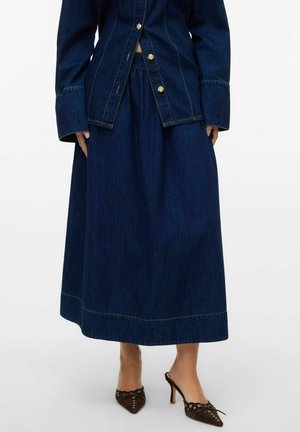Veste en denim avec des boutons dorés, associée à une longue jupe en denim foncé. La tenue présente des coutures contrastées et une texture lisse.