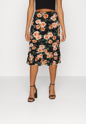 Jupe midi noire à fleurs avec des roses orange, des feuilles vertes et un ourlet à volants ; associée à des talons hauts noirs à brides.