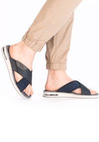 Sandales de plage bleu marine avec des brides croisées, fabriquées en tissu texturé et en matériau synthétique, dotées d'une semelle rembourrée et de poches d'air.