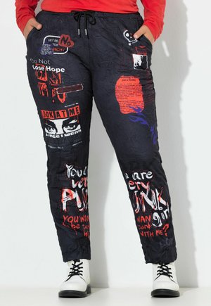 Pantalones negros con estampado que presentan texto en rojo y blanco, con una textura arrugada. Incluyen una cintura con cordón y bolsillos laterales.
