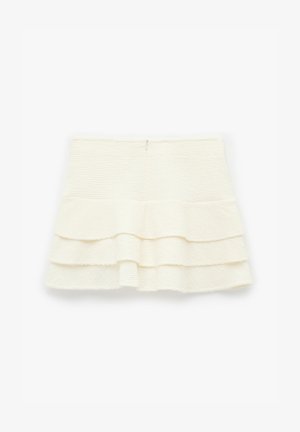 Heller, texturierter Rock in creme mit hoher Taille und zwei schlichten Rüschenschichten auf einem weißen Hintergrund.