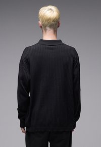 Μαύρο ριμπ πουλόβερ με χαλαρή εφαρμογή, που διαθέτει κλασικό γιακά, μακριά μανίκια και υφασμάτινο πλεκτό σχέδιο.