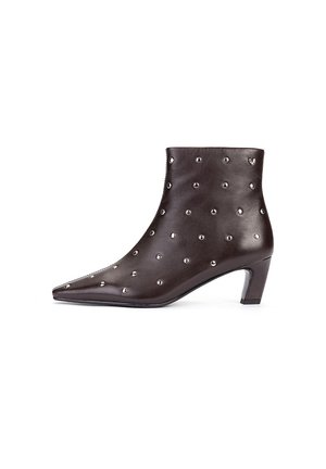 Bota de tobillo de cuero marrón oscuro con puntera puntiaguda, tacón bajo de bloque y tachuelas plateadas uniformemente distribuidas por toda la superficie.