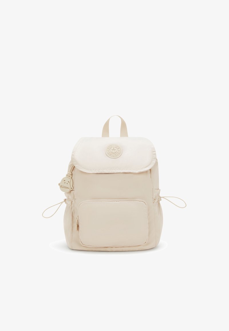Sac à dos beige avec poche zippée devant, fermeture à rabat, écusson rond avec logo, cordons latéraux et un petit porte-clés singe attaché.