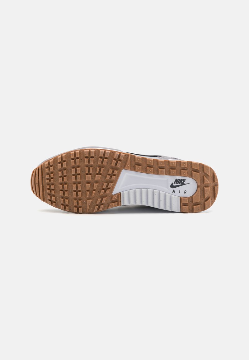 Semelle de chaussure avec une base en caoutchouc brun texturé, une semelle intermédiaire blanche et une marque "Nike Air" visible en noir. Présente un design de motif de semelle.
