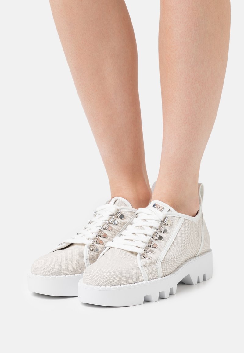 Baskets en toile beige clair avec lacets blancs et semelles en caoutchouc. Elles présentent une tige texturée, un col matelassé et des œillets métalliques.