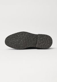 Schwarze Gummisohle mit einer strukturierten, gemusterten Oberfläche und runder Zehenkappe. Sie hat eine flache Silhouette und glatte Seitenkanten.