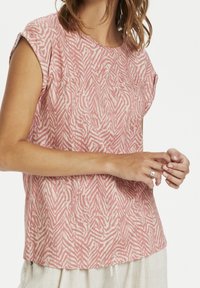 Růžový top s krátkým rukávem se strukturou vlnového bílého vzoru. Kulatý výstřih, volný střih a měkká tkanina s jemným leskem.