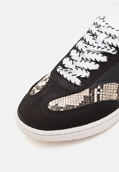 Svarte sneakers med teksturert slangeprinthjørne, hvite snørebånd med svarte detaljer og en kontrasterende hvit gummisåle.