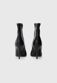 Black leather ankle boots with a high stiletto heel, rear zipper closure, and smooth texture. Features a fitted design and streamlined silhouette.