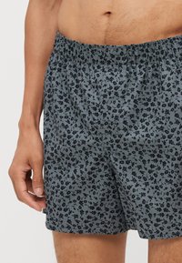 Boxers à motif floral bleu marine, avec une coupe ample et une taille élastique. Fabriqués en coton doux avec une texture lisse.