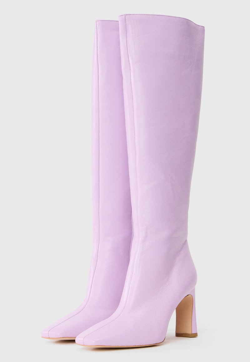 Liliowe kozaki do kolan wykonane z gładkiej skóry, z szpiczastym noskiem i grubym obcasem. Minimalistyczny design bez widocznych elementów metalowych.