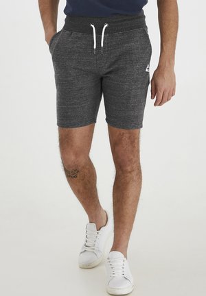 Grå teksturerede shorts med elastisk talje, snørre detaljer, sidelommer og et lille logo-patch. Bæres med hvide sneakers.