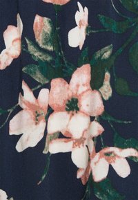 Bloemstof met een donker marineblauwe achtergrond, gekenmerkt door grote roze en witte bloemen, groene bladeren en een geweven textuur.