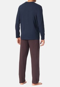 Langärmliges, marineblaues Baumwollhemd kombiniert mit lockeren, gemusterten, kastanienbraunen Schlafanzughosen mit strukturiertem Design. Freizeitliche Loungewear.
