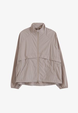 Vaaleanbeige vetoketjullinen tuulitakki, jossa on korkea kaulus, joustavat hihansuut ja vinot sivutaskut, suunniteltu rentoon käyttöön.