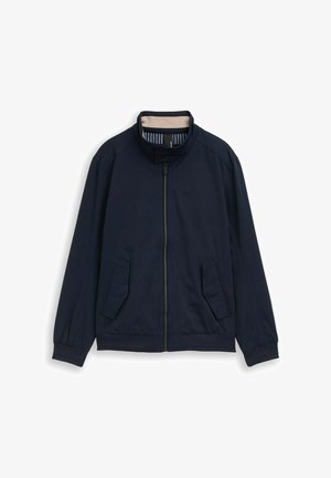 Veste légère bleu marine avec fermeture éclair frontale, col montant à boutons-pression, deux poches à rabat obliques et poignets élastiques.