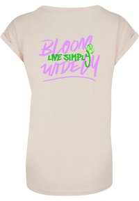 Light pink cotton t-shirt featuring a rounded neckline and rolled sleeves. Back printed with purple and green text: "BLOOM LIVE SIMPLY WIDELY."