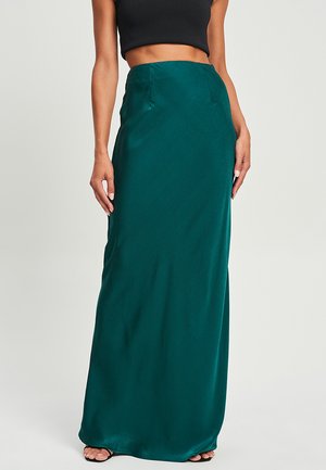 Long, dark green satin skirt with a fitted silhouette and smooth texture. Features a high waist and subtle side pockets.