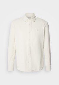 Camicia a maniche lunghe in corduroy bianco con colletto button-down, caratterizzata da un delicato logo ricamato e bottoni frontali per la chiusura.