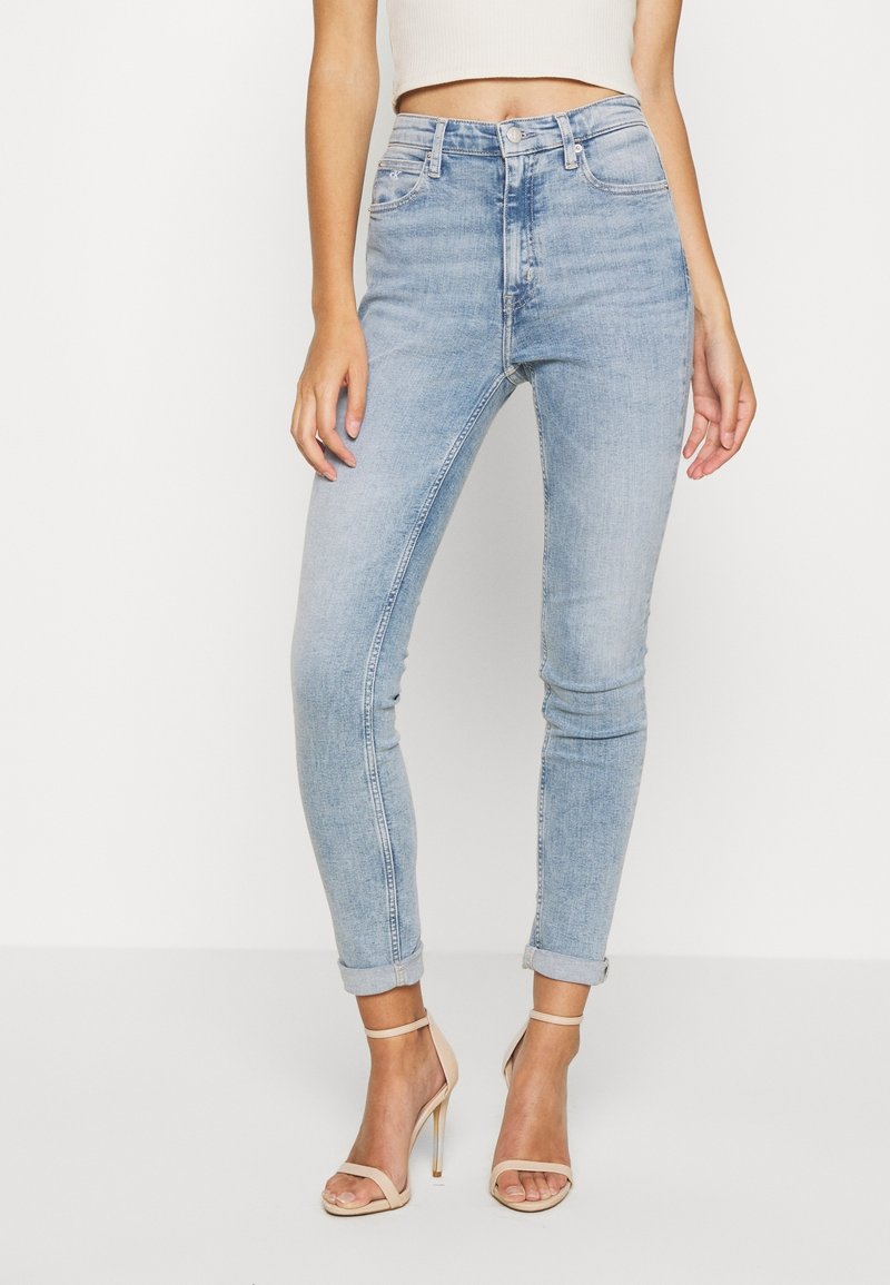 Högmidjade ljusblå jeans med slim fit, blekt utseende, femficksdesign och upprullade fållar. Modellen bär beige klackar med remmar.