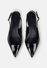 Pantofi slingback din piele patent neagră, cu vârful ascuțit, având o textură netedă, curea ajustabilă și un logo discret pe branț.