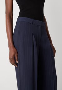 Pantalons marins à rayures avec une taille plate et des poches latérales, dotés d'une texture de tissu lisse et d'une coupe décontractée.