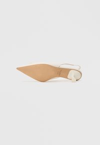 Sapato de salto baixo com tiras em couro branco, bico pontiagudo, salto bloco baixo e sola castanha. Apresenta textura suave e design minimalista.