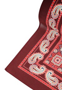 Czerwony materiał w wzory z misternymi motywami paisley w kolorze niebieskim, białym i żółtym; zawiera obrzeża z geometrycznymi kształtami i akcentami.