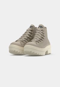 Beige High-Top-Schuhe mit strukturiertem Canvas, runder Zehenpartie und weißer Plateau-Sohle. Schnürung vorne mit Metallösen und gebrandeter Zunge.