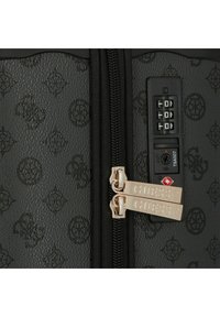 Maletas negras con un diseño estampado y dos cremalleras plateadas etiquetadas como "GUESS". Cuenta con un candado de combinación en el lateral para mayor seguridad.