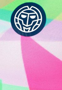 Kleurrijke stof met een geometrisch patroon in roze, groen en blauw, met een zwart cirkelvormig logo van een gestileerd gezicht in het wit.