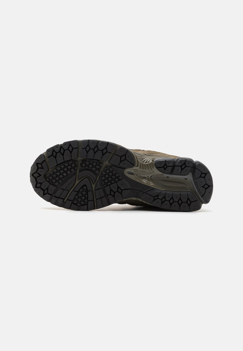 Semelle extérieure de chaussure de trail running en caoutchouc noir texturé avec des reliefs multi-directionnels pour l'adhérence ; semelle intermédiaire grise avec des accents courbés.