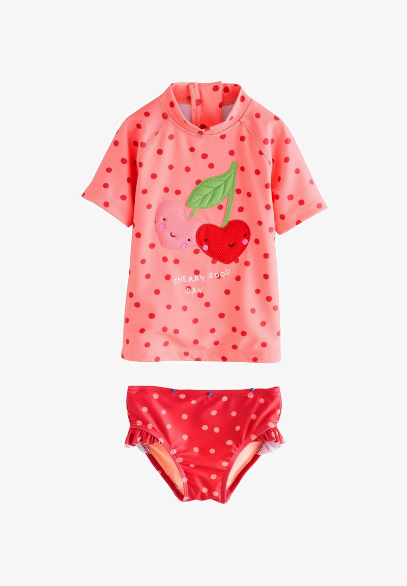 Ensemble de rash guard à manches courtes en rose, orné de pois rouges et d'appliqués cerise. Bas de bikini assortis à pois rouges.