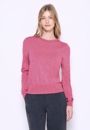 Suéter de manga larga en rosa claro con cuello redondo y puños acanalados. Textura suave, cintura ajustada y sutil abullonamiento en las costuras de los hombros.