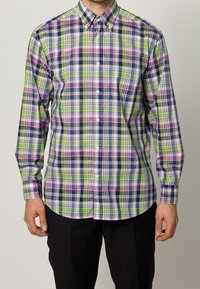 Knappnabb långärmad skjorta i grön, lila, marinblå och vit rutad mönster med krage och knappframslutning. Texturerad bomullstyg.