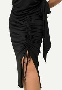 Robe noire avec un design froncé, dotée d'une fente sur le côté et d'un détail à nouer à la taille. Fabriquée dans un tissu lisse et extensible.