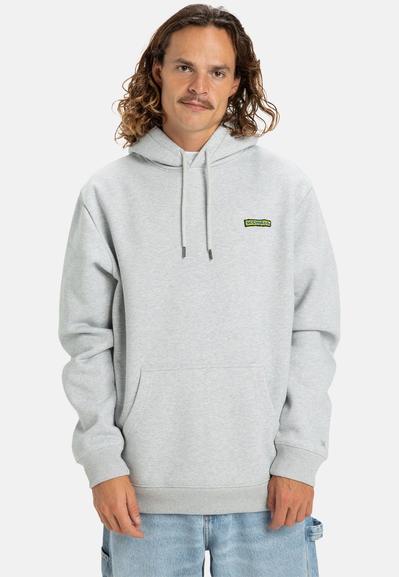 Sudadera gris claro de tela suave, con un bolsillo tipo canguro, cordones y un pequeño parche de logo verde en el pecho.