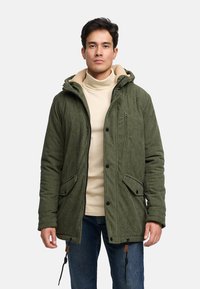 Grüne Cordjacke mit einem fleecegefütterten Kapuzen, Frontreißverschluss, zwei seitlichen Taschen und verstellbaren Kordelzügen am Saum.