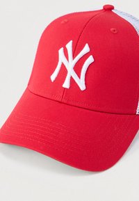 Κόκκινο καπέλο μπέιζμπολ  με στρογγυλεμένο στέμμα, λευκό κεντημένο λογότυπο "NY" και πίσω πάνελ με δίχτυ. Κατασκευασμένο από βαμβάκι με εμφανείς ραφές.