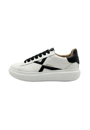 Biały niski sneaker z czarnymi sznurowadłami, czarną pętelką na pięcie, czarnym wzorem "X" po boku oraz beżową podszewką wewnętrzną.