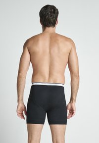 Boxer in cotone nero con elastico bianco in vita. L'elastico presenta la scritta "Jockey" e un branding discreto.